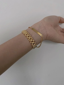 Close-up of gold-plated curb chain bracelet and ID tag set on a female wrist