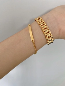 Detail of gold-plated bracelet set with watchband chain and polished metal tag