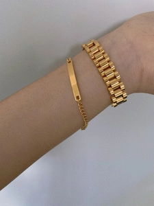 Detail of gold chain bracelets with customizable metal plate on a model's wrist