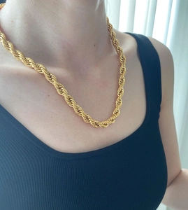 Close-up of 8mm golden rope chain necklace worn on a black ribbed top by a model