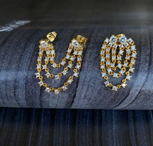 Detailed view of gold triple-layered fringe earrings with sparkling white crystals
