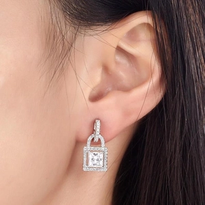 Detailed view of a silver padlock drop earring with cubic zirconia pavé on a model