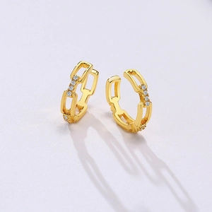 Macro shot of gold chain link earrings with micro-set zircons on textured background