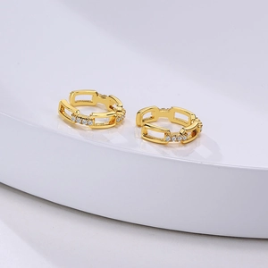 Close-up of golden chain earrings with sparkling cubic zirconia on a white pedestal