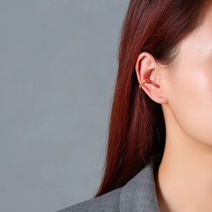 Close-up of a gold-plated ear cuff featuring three inlaid white zircon stones on a model
