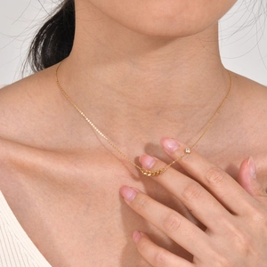 Close-up of 18K gold chain necklace featuring a zircon diamond and linked ring pendant