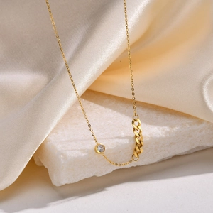 Detail of 18K gold Cuban link chain with sparkling zircon on white marble background
