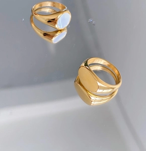 Detail of gold signet rings featuring polished finish and white shell inlay on mirror surface