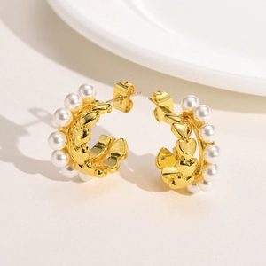 Detailed side view of golden C-shaped layered earrings with pearls and heart patterns
