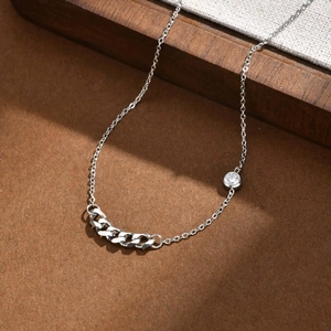 Detailed macro view of silver chain necklace featuring a curb link and sparkling zircon stone