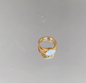 Detailed close-up of golden signet ring featuring an oval light blue opal inlay