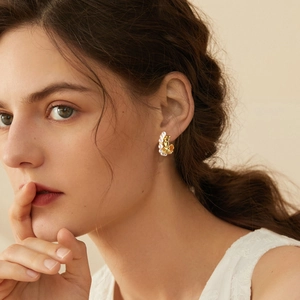 Elegant gold C-shaped earrings with micro-pearl inlay shown on model in soft lighting
