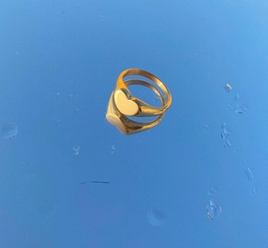 Golden heart signet ring reflecting on a creative blue water surface with ripples