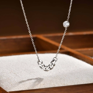 Macro shot of silver curb link chain with a bezel-set zircon stone on a jewelry pad