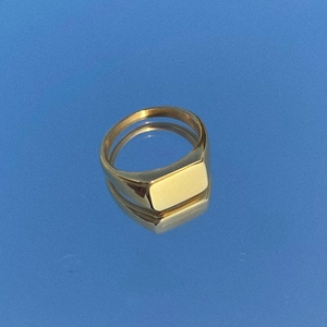 Detailed view of a gold rectangular signet ring with a polished mirror finish on blue glass