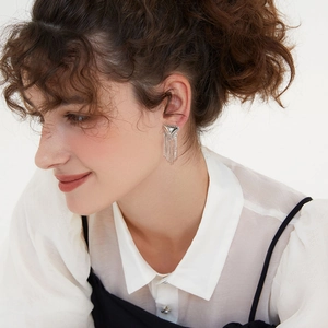 Detailed view of silver triangle tassel earrings worn by model for style and scale