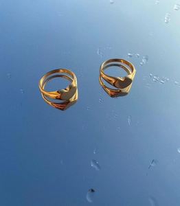 Macro shot of two golden heart-shaped rings reflecting on a blue mirrored surface