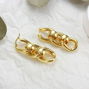 Detail shot of chunky gold chain drop earrings with interlocking links on white paper