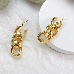 Macro detail of gold link chain earrings featuring polished chunky oval hoop design