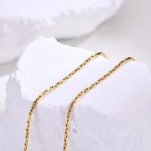 Gros plan sur la chaîne de clavicule en acier doré de 1 mm avec texture segmentée fine