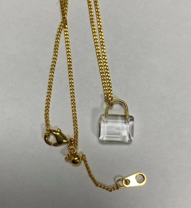 Detail of adjustable gold necklace with a transparent rectangle padlock pendant and clasp