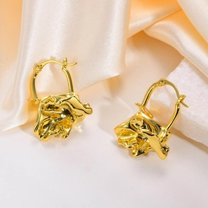Detail of golden brass hoop earrings with artistic pleated texture on silk background
