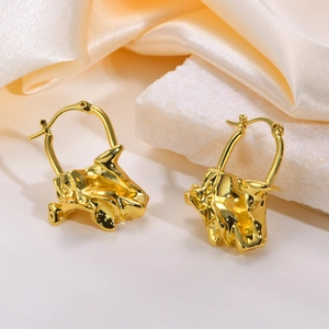 Detail of gold irregular crumpled metal earrings on satin fabric and stone background