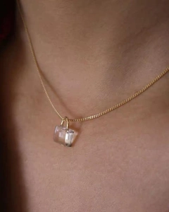 Macro detail of gold clavicle chain with transparent square stone pendant on neck