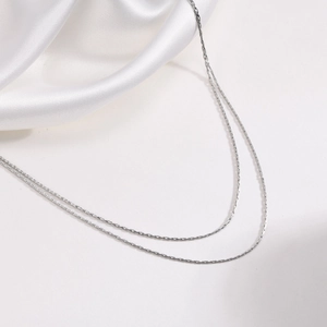 Macro d'une chaîne de clavicule 1mm en acier inoxydable argenté sur soie blanche