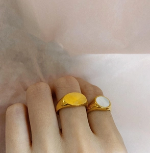 Detail of gold minimalist rings featuring a white shell inlay on a model's hand