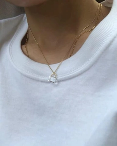 Close-up of minimalist gold padlock necklace with transparent stone on model neckline
