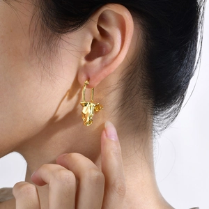 Detail of gold molten texture earring with U-shaped latch on model with soft lighting