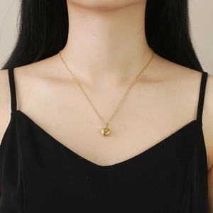 Elegante collana con ciondolo a cuore dorato su catena minimalista indossata da modella
