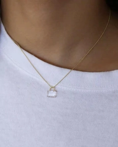 Detail of a gold padlock necklace featuring a transparent crystal pendant on a gold chain