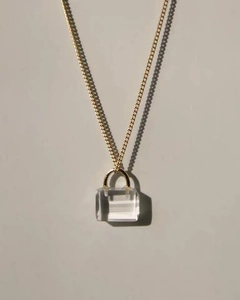 Close-up of a mini handbag pendant with clear stone and gold chain necklace