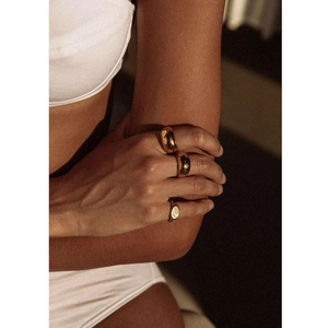 Close-up of a model wearing three chunky gold rings with a polished minimalist aesthetic