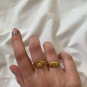 Close-up of a gold starburst ring with crystal and a minimalist oval signet ring