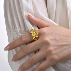 Detailed close-up of a wide gold brass ring featuring a unique irregular wrinkled texture