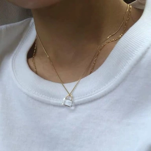 Double layered gold necklace with square transparent crystal padlock pendant on a model