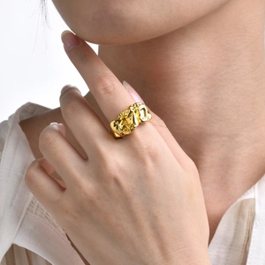 Detailed view of chunky gold ring with irregular lava texture on a model's finger