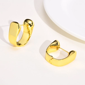 Detailed close-up of thick gold-plated U-shaped stud earrings with a glossy polished finish