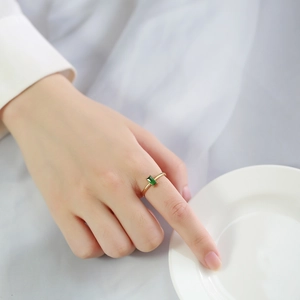 Detail of a thin gold titanium ring with an emerald green zircon on a female hand