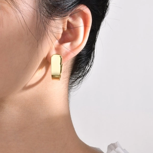 Close-up of chunky gold rectangular earring featuring a high-polish mirror finish on model
