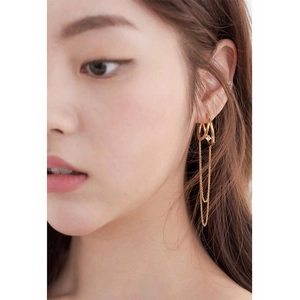 Macro detail of gold double ring earrings with sparkling zircon and long tassel chains