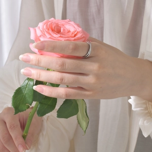 Silver interlocking double band titanium steel ring on finger with pink rose detail