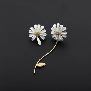 Detailed view of daisy earrings with white petals, yellow centers, and golden stem