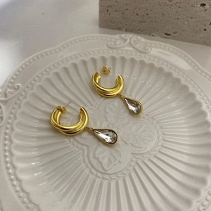 Detail of gold-plated copper hoop earrings with teardrop zirconia in a ceramic dish