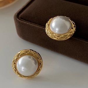 Detail of vintage gold-plated round earrings with large pearls and quilted texture