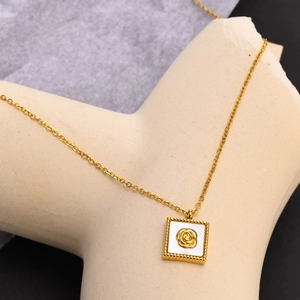 Vue macro d'un pendentif carré doré avec relief de rose sur incrustation nacre