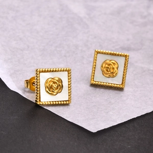 Boucles d'oreilles carrées dorées avec relief rose et bord perlé sur fond texturé